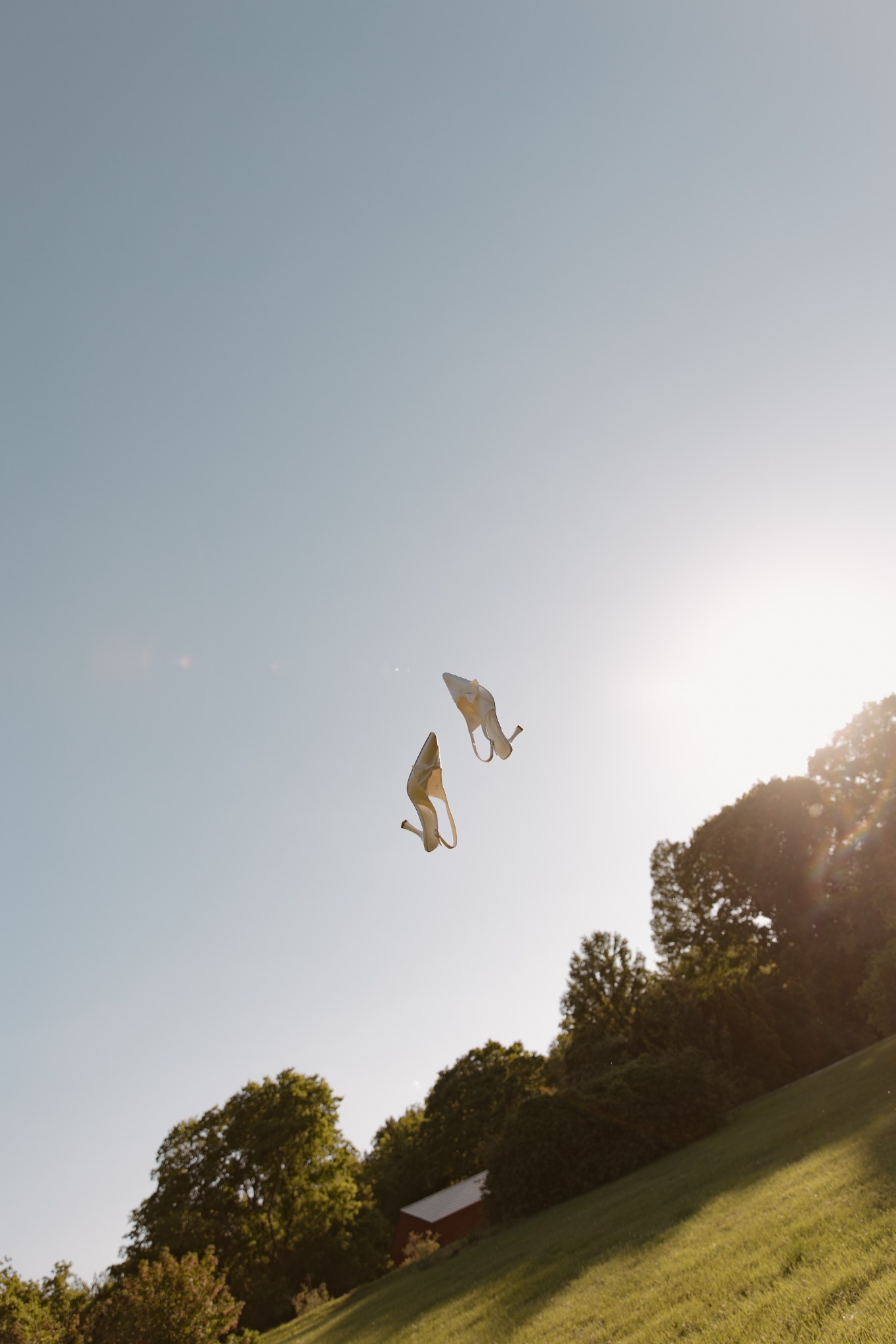 A bride's shoes tossed into the sunlit sky